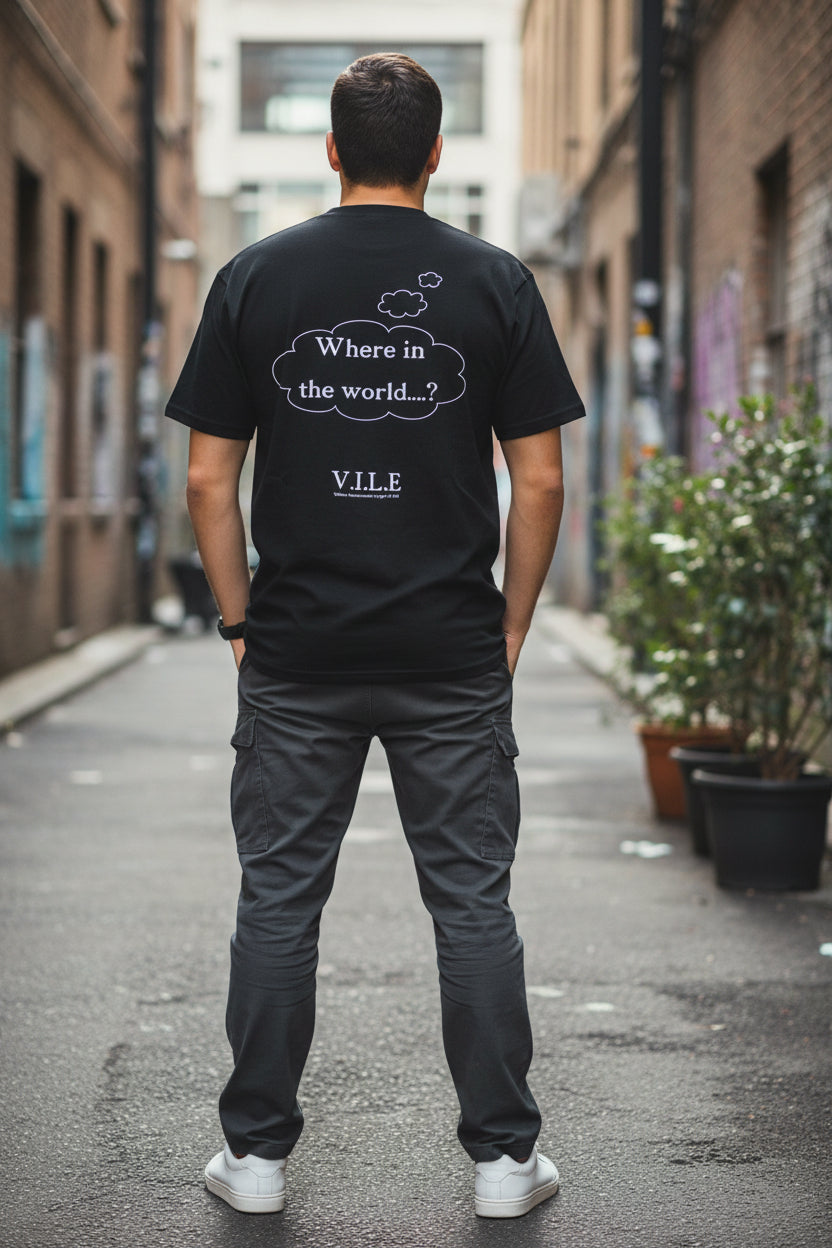 A black graphic t-shirt hanging on a hanger in front of a window. The shirt features a white printed thought bubble with the text 'Where in the world.